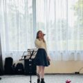 Na zdjęciu dziewczyna śpiewająca na scenie.