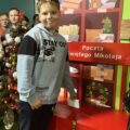 Zdjęcie przedstawia chłopca, który wrzuca swój list do skrzynki z pocztą do św. Mikołaja. W kolejce czeka reszta dzieci na swoją kolej.