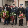 Zdjęcie przedstawia zaproszonych gości z wiązankami.