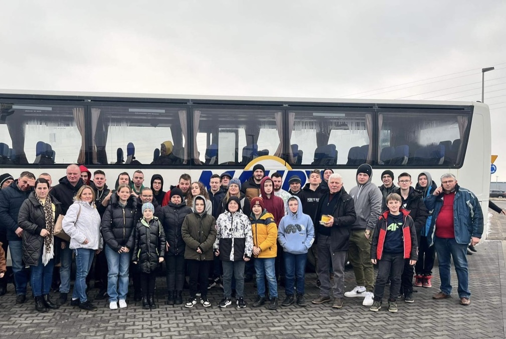 Wspólne zdjęcie uczestników wydarzenia na tle autobusu.