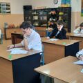 Uczestnicy siedzą w ławkach i wypełniają testy.