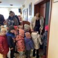 Zdjęcie przedstawia dzieci, które odbierają upominki w postaci kolorowanek i kredek wychodząc ze sali sesyjnej.