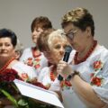 Kobieta mówi przez mikrofon, w tle inne panie.