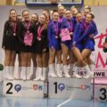 Grupa mażoretek pozuje do wspólnego zdjęcia na stopniach podium