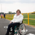 Zdjęcie przedstawia uśmiechniętego Maksyma Kruka na ścieżce poruszającego się na wózku.