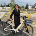 Fotografia przedstawia Panią Dyrektor szkoły w Radomierzu, która uśmiechnięta pozuje do zdjęcia z rowerem na ścieżce.