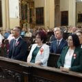 Uczestnicy wydarzenia siedzą w ławkach kościelnych