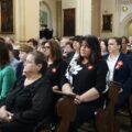 Uczestnicy wydarzenia siedzą w ławkach kościelnych