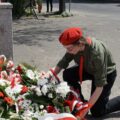 Harcerz układa kwiaty pod pomnikiem.