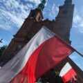 Flaga na 1 planie, w tle kościoł