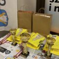 Na zdjęciu nagrody dla zwycięzców turnieju. Wśród nich znajdują się trzy puchary z medalami. Oprócz tego kamizelki odblaskowe oraz vouchery na rowerki wodne, na zajęcia z piłki nożnej oraz z judo.