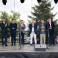 Grupa mężczyzn w garniturach na scenie, klaskają.