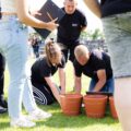 Dwie osoby biorą udział w konkurencji, nad nimi sędzia oraz osoby dopingujące.