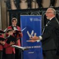 Koncert chóru chłopięcego i męskiego. Na pierwszym planie dyrygent.