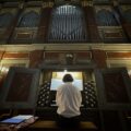 Organista gra na organach, zdjęcie tyłem.