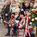 Uczestnicy wydarzenia, na pierwszym planie dziewczynki z flagami.