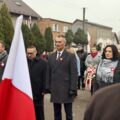 Uczestnicy wydarzenia składają kwiaty pod pomnikiem.