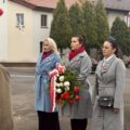 Uczestnicy wydarzenia składają kwiaty pod pomnikiem.