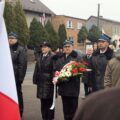 Uczestnicy wydarzenia składają kwiaty pod pomnikiem.