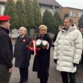 Uczestnicy wydarzenia składają kwiaty pod pomnikiem.
