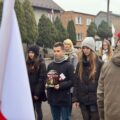 Uczestnicy wydarzenia składają kwiaty pod pomnikiem.