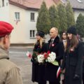 Uczestnicy wydarzenia składają kwiaty pod pomnikiem.