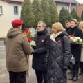 Uczestnicy wydarzenia składają kwiaty pod pomnikiem.