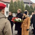 Uczestnicy wydarzenia składają kwiaty pod pomnikiem.
