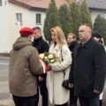 Uczestnicy wydarzenia składają kwiaty pod pomnikiem.