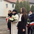 Uczestnicy wydarzenia składają kwiaty pod pomnikiem.