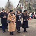 Uczestnicy wydarzenia składają kwiaty pod pomnikiem.