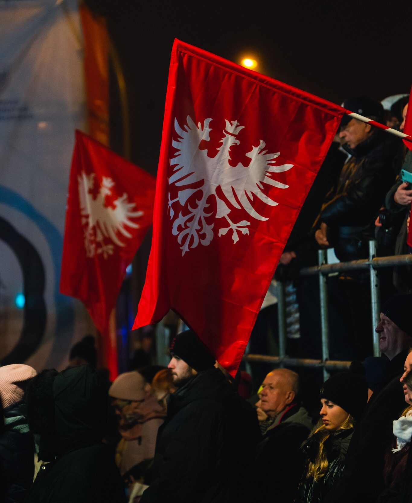 Na zdjęciu dwie flagi powstania wielkopolskiego. Na fotografii widoczni także ludzie.