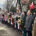 Na zdjęciu osoby uczestniczące w uroczystości na rynku, wśród nich m.in. zastępca wójta Waldemar Kalitka, przewodnicząca rady gminy Monika Maćkowiak, wicestarosta Wolsztyna i burmistrz Wolsztyna. Niektóre osoby trzymają wiązanki kwiatów.