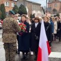 Na zdjęciu żołnierz odbiera wiązankę kwiatów od delegacji ze szkoły.