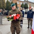 Na zdjęciu żołnierz składa wiązankę pod pomnikiem na rynku.