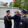 Na zdjęciu minister Wiesław Szczepański przypina odznakę. jednemu ze strażaków.