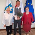 Na zdjęciu zastępca wójta wraz z dwiema panami z dziennego domu pomocy z Błotnicy. Zastępca trzyma w ręce bukiet kwiatów i laurkę.