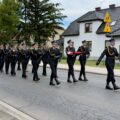 Na zdjęciu strażacy podczas przemarszu wzdłuż ulicy.
