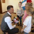 Na zdjęciu zastępca wójta Waldemar Kalitka przyjmuje upominki w postaci kwiatów i kartki z życzeniami od trójki przedszkolaków z Przemętu.
