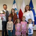 Wspólne zdjęcie zastępcy wójta z trójką przedszkolaków i dyrektorką przedszkola. Zastępca trzyma w ręce kwiaty i laurkę.