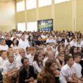 Zdjęcie przedstawia uczniów, rodziców i nauczycieli siedzących na sali gimnastycznej.