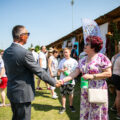 Na zdjęciu wójt wita się z z radną Elżbietą Witą. W tle osoby obecne na wydarzeniu i stoiska z jedzeniem.