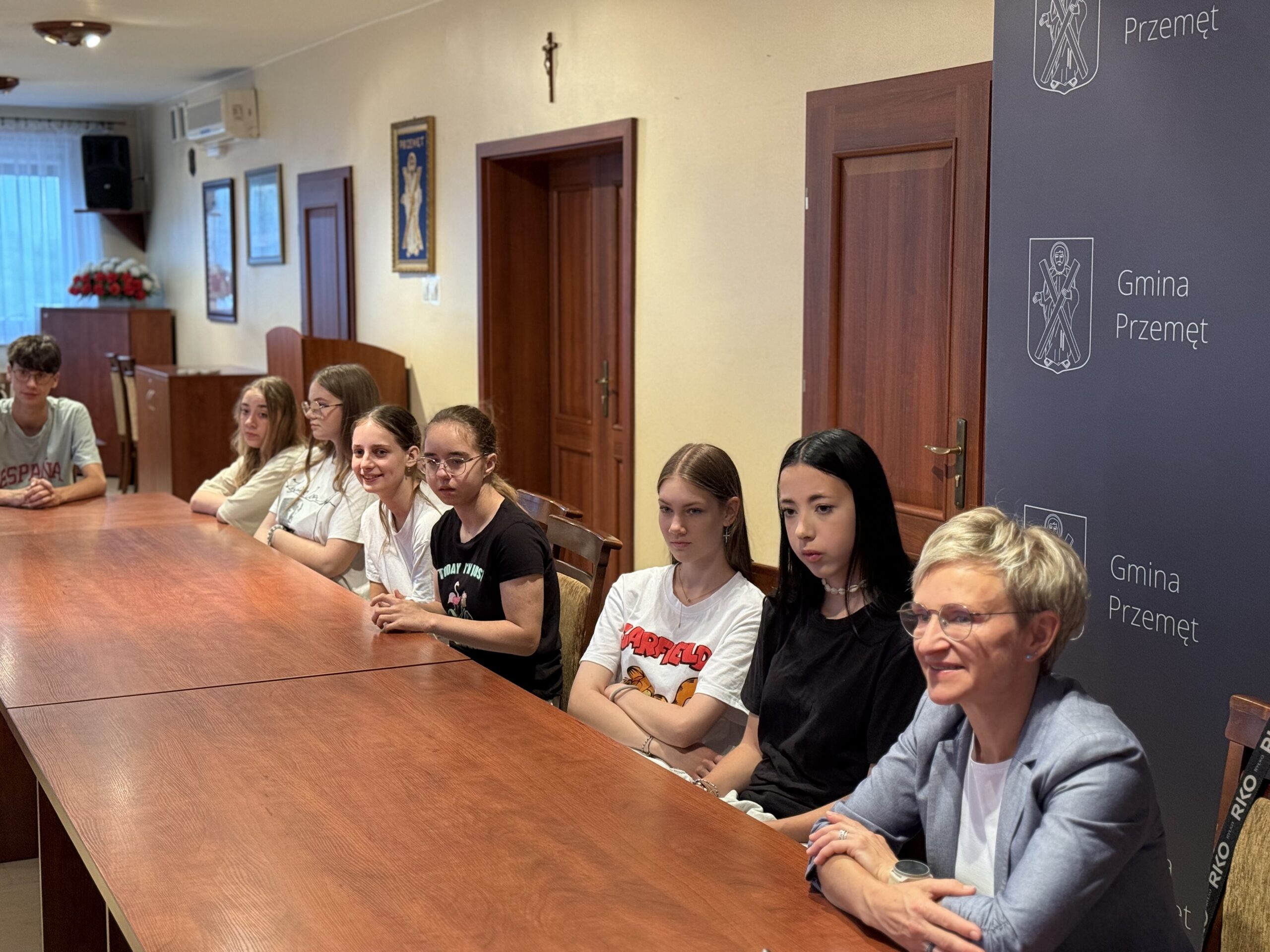 Na fotografii uczniowie oraz nauczycielka siedzą w sali sesyjnej w urzędzie.