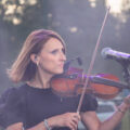 Na zdjęciu kobieta, która gra na skrzypcach podczas koncertu.