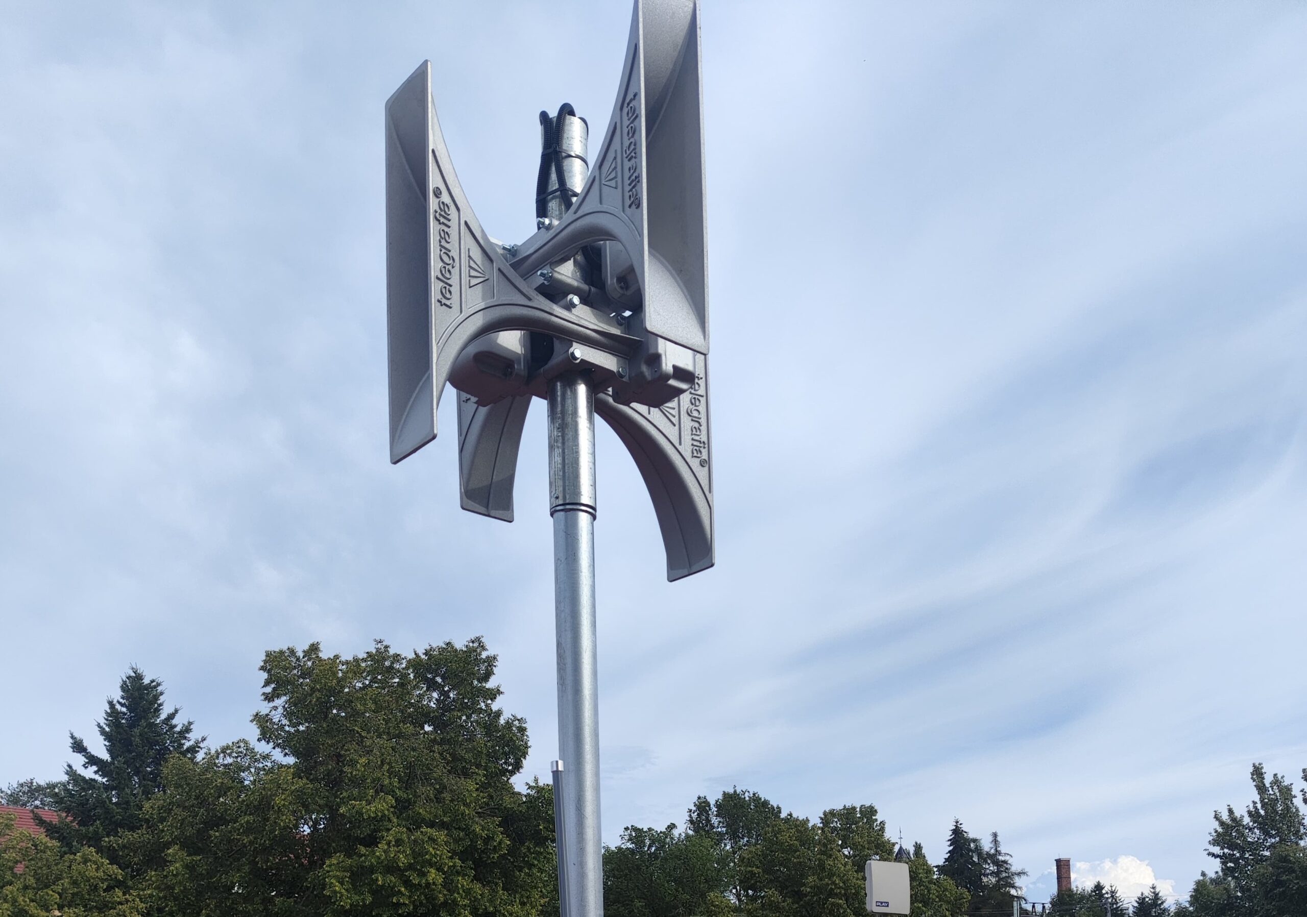 Nowoczesna syrena elektroniczna zamontowana na maszcie. Urządzenie posiada charakterystyczne cztery tuby głośnikowe.