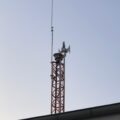 Na zdjęciu syrena zamontowana na stalowej kratownicy, będącej wieżą alarmową przy remizie. U góry znajduje się zarówno nowa syrena, jak i starszy model sygnalizacyjny, co ukazuje modernizację infrastruktury.