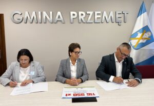 Na fotografii wójt i skarbnik gminy podczas podpisywania umowy. Na zdjęciu także pani Barbara Mroczkowska. W tle srebrny napis: "Gmina Przemęt".