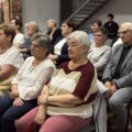Na fotografii widoczni są seniorzy siedzący w sali podczas wykładu.