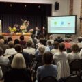 Na zdjęciu dr Mirosław Radoła podczas przeprowadzania wykładu. Na projektorze wyświetlana jest jego prezentacja. Na zdjęciu widać także seniorów, którzy słuchają wykładu.