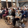 Na zdjęciu wójt, pani Agnieszka Klugiewicz, pani Elżbieta Wita, prof. UAM dr hab. Sylwia Jaskulska oraz seniorzy. Wszyscy siedzą na widowni w sali.